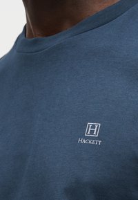 Μπλε ναυτικού βαμβακερό T-shirt με στρογγυλή λαιμόκοψη και κοντά μανίκια. Διαθέτει μικρό λευκό κεντημένο λογότυπο "Hackett" στο στήθος.