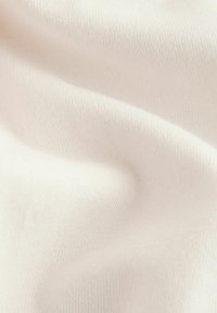 Cremefarbener Stretchstoff mit glatter Textur und feinem Rippmuster, der sanfte Drapierungen und weiche Falten zeigt.