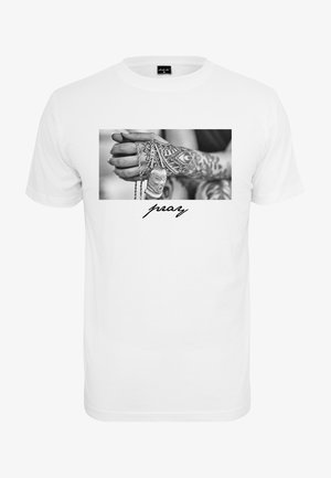 Tricou alb din bumbac, având o fotografie alb-negru cu mâini care țin un colier cu un pandantiv. Cuvântul "roagă-te" este imprimat în stil cursiv dedesubt.