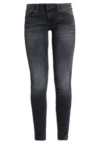 Jeans pitillo de mezclilla negra con textura suave, diseño de cinco bolsillos y cierre con botones, con un sutil desgaste a lo largo de las piernas.