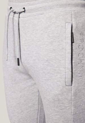Szare spodnie dresowe z elastycznym pasem, bocznymi kieszeniami i haftowanym logo. Materiał ma miękką, gładką fakturę z lekkim melanżem.