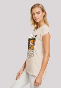 Beige cotton t-shirt with a short sleeve, featuring a graphic design of a character and "STAR WARS" text in black at the front.
