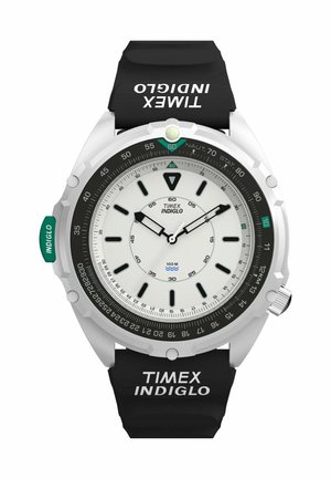 Round Timex Indiglo watch with black strap, white dial, black hour markers, silver bezel, and green Indiglo light button on the left side.