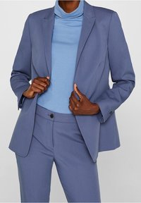 Ljusblå kavaj med matchande byxor, som har en elegant design, skräddarsydd passform och subtila sömdetaljer. Slät tygkänsla.