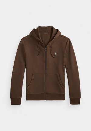 Brun zip-up hoodie med dragsko på huvan, framfickor och en liten logotyp på vänster bröst. Tillverkad av mjukt tyg med ribbade ärmslut.