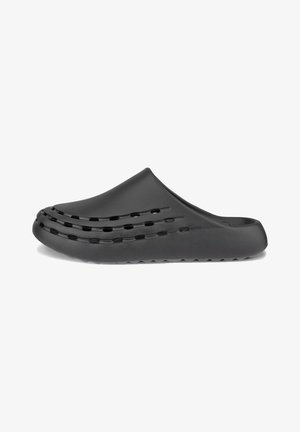 Mustat, muotoillut liukupohjaiset kengät, joissa on sileä pinta, rei'itetty muotoilu sivuilla ja teksturoitu pohja pidon varmistamiseksi. Kevyt, unisex-tyyli.