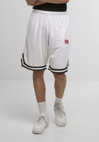 Hvide basketballshorts med sorte sidelogo-striber og et rødt logo-patch. Lavet af et letvægts, åndbart stof. Elastisk talje.