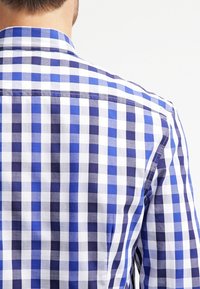 Blauw-wit geruit shirt met een mix van grote en kleine vierkanten, gemaakt van katoen, met een knoopsluiting bij de kraag en een afgeronde zoom.