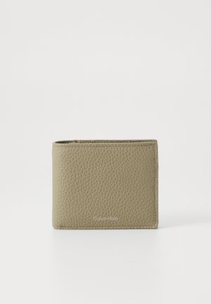 Calvin Klein kortelių laikiklis iš tekstūruotos šviesiai smėlinės odos, stačiakampio formos, su logotipu priekyje ir tvarkingais kraštais.