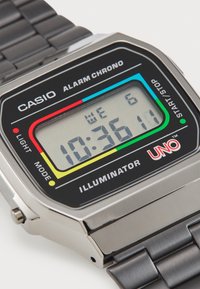 Digital Casio-klokke med svart skjerm, metallisk sølvhus og svart metall lenkebånd. Har fargede knapper og digitalt display.