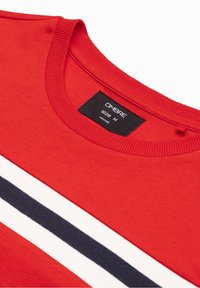 Sudadera roja con cuello redondo acanalado; presenta rayas horizontales en blanco y azul marino. La etiqueta indica tamaño M y el nombre de la marca "OMBRA."