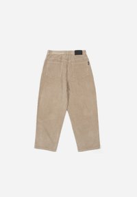 Beige cordfløyelsbukser med vide ben, to baklommer og en svart midjebåndslabel. Teksturert stoff med subtile ribbedetaljer.