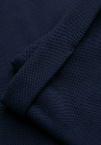 Tissu en tricot bleu marine foncé plié pour montrer un motif texturé, tissé serré et des qualités de matériau doux et flexible.