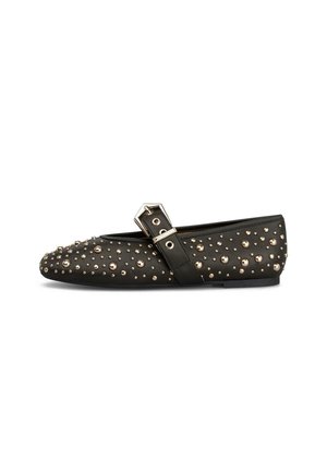 Zapato plano negro con una correa y tachuelas redondas plateadas que cubren uniformemente la superficie, mostrado de lado sobre un fondo blanco.