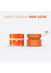 Due barattoli di Origins GinZing Brightening Eye Cream, uno con base bianca e accento arancione, e l'altro di un arancione solido uniforme.