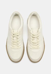 Weiße Ledersneaker mit glatter Oberfläche, abgerundetem Zehenbereich, durchbrochenen Details und hellbraunen Gummisohlen. Mit flachen Schnürsenkeln und minimalem Branding.