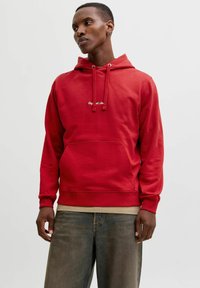 Hoodie rouge en mélange de coton, avec une poche avant et une capuche avec cordon. Il présente un subtil logo blanc sur la poitrine. Coupe décontractée.