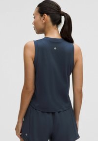 Temno modra športna majica brez rokavov z mrežastimi detajli na rami in logotipom na hrbtu. Mehka, lahka tkanina.