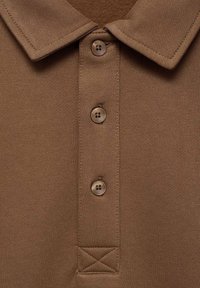 Braunes Poloshirt mit flachem Kragen, dreiknöpfiger Knopfbrusttasche mit passenden Knöpfen und gestickten Akzenten unter den Knöpfen. Glatte Textur.