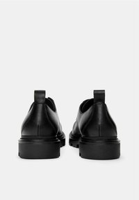 Pantofi negri din piele cu un finisaj neted, cu un design la gleznă scăzut, cu urechi de prindere și talpă groasă din cauciuc. Fără modele vizibile sau accente suplimentare.