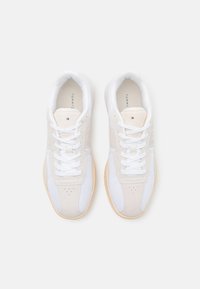 Sneaker bianche e beige chiaro realizzate con materiali in rete e suede, dotate di lacci tondi, accenti perforati e suola in gomma.