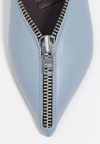 Niebieski skórzany but w szpic z metalicznym suwakiem wzdłuż górnej krawędzi i teksturowaną podszewką. Gładkie wykończenie z eleganckim wzornictwem.