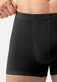 Czarne elastyczne bokserki wykonane z teksturowanego materiału, z logo na pasku oraz dopasowanym krojem, z widocznymi detalami szwów.