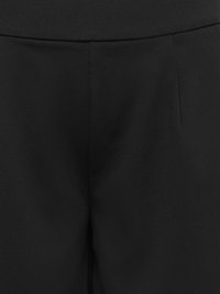 Primer plano de la parte delantera de pantalones negros mostrando la cinturilla y detalles de la costura central.