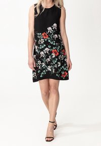 Schwarzes ärmelloses Kleid mit floralem Muster in Rot, Weiß und Grün. Der Stoff ist glatt, und die A-Linie endet oberhalb der Knie.