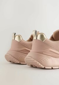 Rózsaszín sportcipő, texturált bőrrel és fényes arany részletekkel. Párnázott bokarésze és gumis talpa van, amely bordázott a jobb tapadás érdekében.