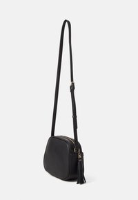 Borsa a tracolla in faux pelle nera con forma arrotondata, zip dorata e tracolla regolabile. Presenta un accento a frange sul lato.