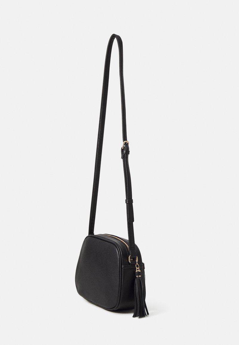 Borsa a tracolla in faux pelle nera con forma arrotondata, zip dorata e tracolla regolabile. Presenta un accento a frange sul lato.