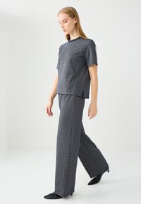 Blauwe outfit met een patroon, bestaande uit een losse korte mouwen top en wijde broek, gemaakt van lichte stof met een geometrisch ontwerp.