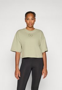 Helles olivgrünes, cropped T-Shirt aus weichem Stoff, mit Rundhalsausschnitt und kurzen Ärmeln, versehen mit einem runden Logo-Druck auf der Vorderseite.