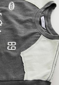 Grå hoodie med ljusgrå axelpaneler, med vita broderade siffror "68" och logotyp. Mjuk tyg med rundad halsdesign.