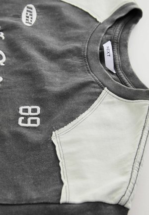 Sweatshirt gri cu panouri ușor gri pe umeri, având brodate în alb cifrele "68" și logo-ul. Material moale cu design de gât rotund.