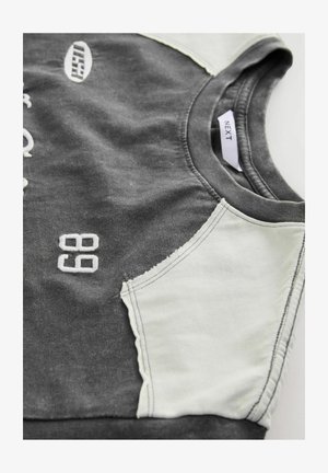 Grå sweatshirt med lysegrå skulderpaneler, med hvide broderede tal "68" og logo. Blødt stof med rund hals.