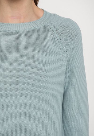 Pulover tricotat de culoare albastru deschis, cu guler rotund ribatat și mâneci raglan, având un model de țesătură texturată și o croială relaxată.