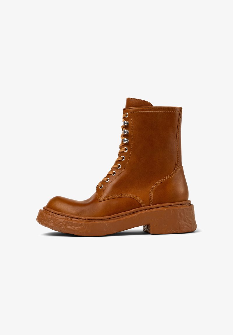 Bottines en cuir marron avec bout arrondi, lacets à l'avant, œillets en métal argenté et semelle épaisse texturée. Fini lisse avec des accents de coutures simples.