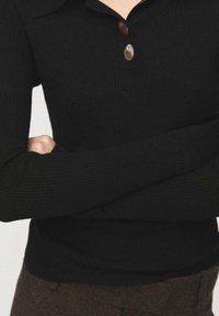 Pulover negru cu dungi tricotate, cu guler, având trei nasturi maro la gât și mâneci lungi, evidențiind un design strâmt pe corp.