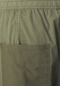 Olivengrønne shorts lavet af letvægtsstof, med elastisk talje og en stor lommelap på bagsiden.