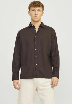 Dunkelbraunes Hemd mit Knöpfen, Kragen, langen Ärmeln und weißen Knöpfen. Kombiniert mit hellbeigen Shorts. Einfaches Design und glatte Textur.