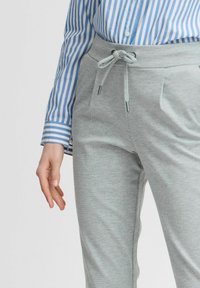 Grå sweatpants har dragsko i midjan, sidofickor och ett mjukt, texturerat material, tillsammans med en blå och vit randig skjorta.