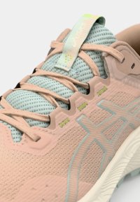 Zapatilla de running ligera en rosa y azul, con parte superior de malla, acentos texturizados y una suela de goma con ranuras flexibles para mayor agarre.