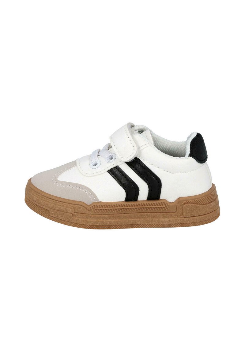Zapatilla blanca con rayas negras, suela de goma, correa de Velcro y diseño con cordones. Presenta una superficie texturizada y punta redondeada.
