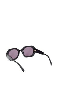 Gafas de sol octagonales negras con lentes morados, montura de plástico suave y sutiles acentos de hardware dorado en las bisagras.