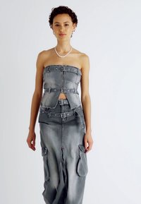 Conjunto de dos piezas de denim gris que incluye un top sin tirantes con botones a presión y una falda ajustada con bolsillos laterales y una abertura. Textura suave.