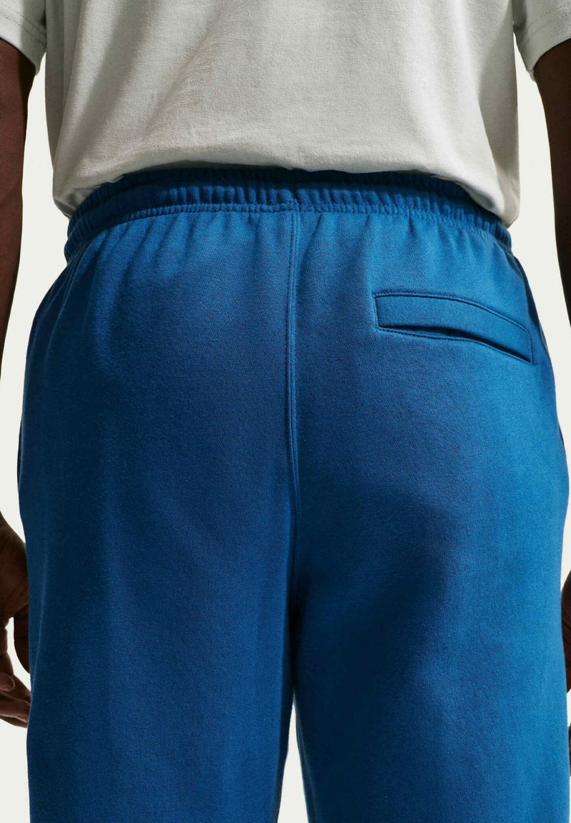 Blåa bomulls joggingbyxor med elastisk midja, utrustade med en bakficka och en slät textur. Stylade med en avslappnad look.