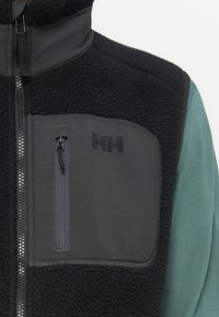 Fleece vest in zwart en grijs, met een hoge kraag, een ritsvak en een contrasterende textuur. Logo op de borst weergegeven.
