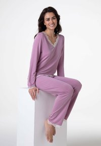 Completo da loungewear lilla con maniche lunghe e pizzo sul collo e sui polsini. Tessuto morbido, vestibilità comoda e pantaloni lunghi.
